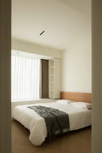 Modern minimalist bedroom featuring a wooden bed frame and white bedding.