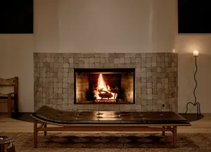 Minimalist living room with a stone fireplace, wood bench, and candle.