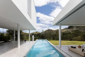 A modern poolhouse featuring concrete and glass materials with a swimming pool.