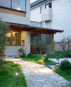A minimalist residential exterior featuring stone pathways and lush greenery.