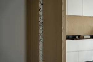 Minimalist kitchen interior with a marble backsplash and wooden cabinets.