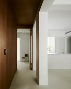 Minimalist living room with concrete floor and walls, featuring a single black chair in the background.