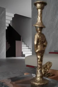 Modern interior space featuring a metallic statue on a shelf, with a staircase in the background.