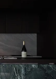 A modern kitchen featuring marble countertops and dark cabinets with a bottle of Moula Chardonnay.