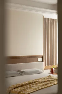 Minimalist bedroom with a bed featuring a fabric blanket, white bedding, and a wooden headboard.