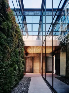 Modern industrial-style entranceway with concrete walls and a glass ceiling, featuring a green living wall on one side.