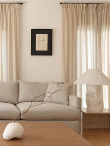 A living room with neutral-toned curtains, a light-colored sofa, and a wooden coffee table.