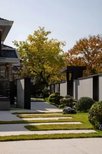 A modern, minimalist residential entryway featuring concrete elements and a pathway with grass patches.