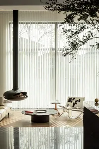 Modern living room featuring transparent curtains, minimalist coffee table, and a stylish hanging fireplace