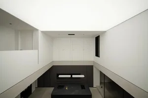 Modern minimalist kitchen with concrete elements, featuring sleek black appliances and a central island with a dark counterto