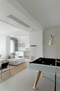 Modern minimalist living room and game room with a white pool table and a comfortable sofa.