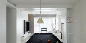 A modern living room with white walls, a black pool table, and a flat-screen TV.