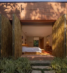 A well-lit bedroom with a wooden floor and a bed, featuring minimalist design and modern furniture.