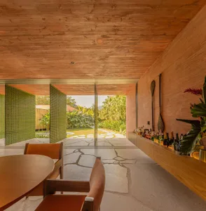 A modern residential space with wooden interior design, featuring a dining area, bar counter, and open layout.