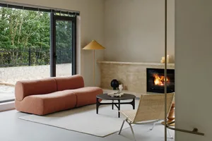 A modern living room featuring textured fabric furniture, a fireplace, and a concrete wall. Overlooking natural greenery outs