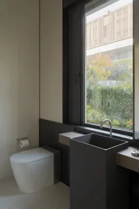 Modern bathroom with minimalist design, featuring a sleek, black rectangular sink and a white toilet, complemented by a large