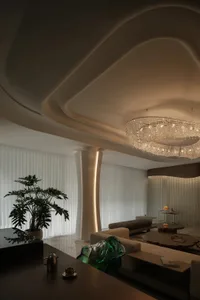 A modern living room with white textured walls and ceiling, featuring a chandelier, couches, and a potted plant.