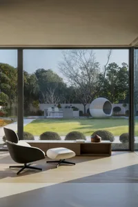 A modern minimalist living room with a large window overlooking a landscaped garden.