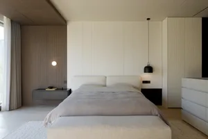A minimalist bedroom with a textured wall paneling and a modern bed, featuring a hanging lamp and a floating nightstand.