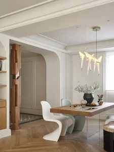 A modern dining room with a wooden table and chairs, featuring contemporary lighting and decor.