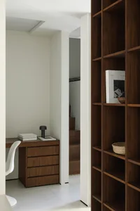 A modern interior space featuring a wooden bookshelf and white furniture.