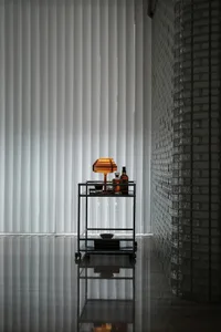 A minimalist bedroom featuring glass blinds, a concrete floor, and a brick wall.