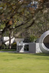 A modern outdoor patio with metal planters, grass, and stone elements.