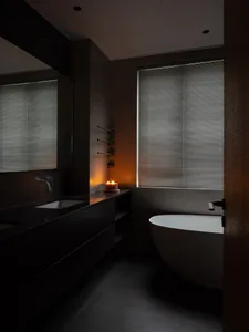 A modern bathroom with a concrete finish, featuring a freestanding bathtub, a floating vanity with a dark countertop, and a l