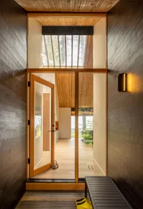 A modern entryway featuring wooden walls and a glass door with a skylight above.