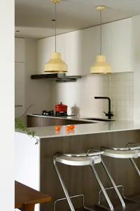 A spacious, modern kitchen with white-painted walls and ceiling, wooden flooring, and glass elements.