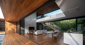 Modern living, dining, and kitchen space featuring wooden floors and marble elements.