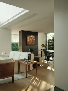 Modern living room featuring hardwood flooring, white sofas, and wooden side table with books and decorative items.
