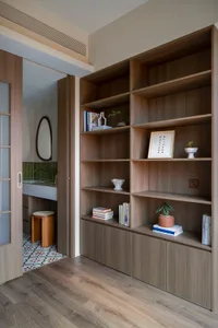 A modern living room featuring wooden shelves with books and decorations.