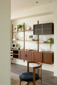 A modern office shelving unit made of wood, featuring a variety of functional elements such as cabinets, shelves for plants a