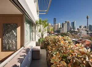 A modern terrace featuring potted plants and greenery, overlooking a city skyline.