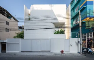A modern white concrete residential house with a clean, minimalist architectural design.