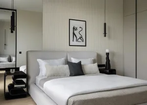 A minimalist bedroom with a bed made of fabric and metal, surrounded by wooden flooring.