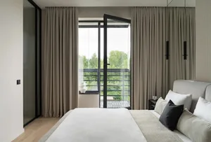 Modern bedroom with neutral color palette and large window with curtains.