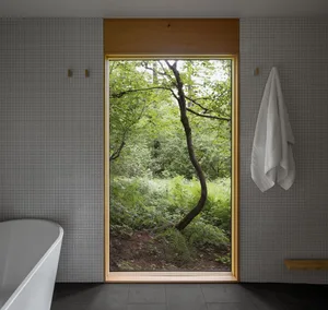 Modern bathroom with a clear glass window showcasing a lush forest view.