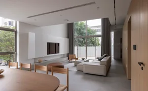 Modern living room with concrete walls, minimalist furniture, and large windows.