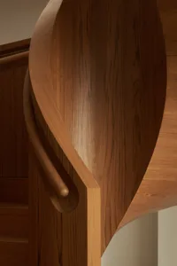 A close-up view of a curved wood staircase handle and wooden steps.