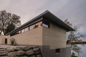 Modern building made of brick with large windows overlooking a body of water.