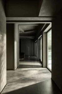 A modern corridor with concrete walls and flooring, featuring a narrow passageway and a gap in the floor.