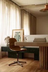 A modern home office with a concrete desk, marble bench, and glass elements.
