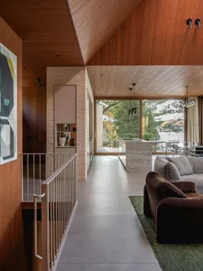 A modern living room and kitchen with concrete flooring and wooden walls and ceiling.
