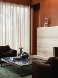 Modern living room with marble coffee table, concrete fireplace, and wooden furniture.