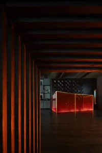 A modern office reception area featuring a glass wall with geometric patterns illuminated from behind.