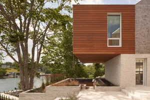 A modern residential exterior featuring a combination of wood, concrete, and brick materials.