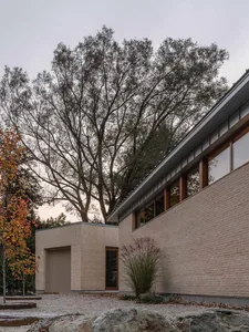 Modern residential exterior with brick walls and concrete roof, surrounded by gravel and rock landscaping.