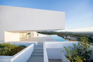 A modern residential architecture featuring a concrete structure and infinity pool overlooking scenic landscape.
